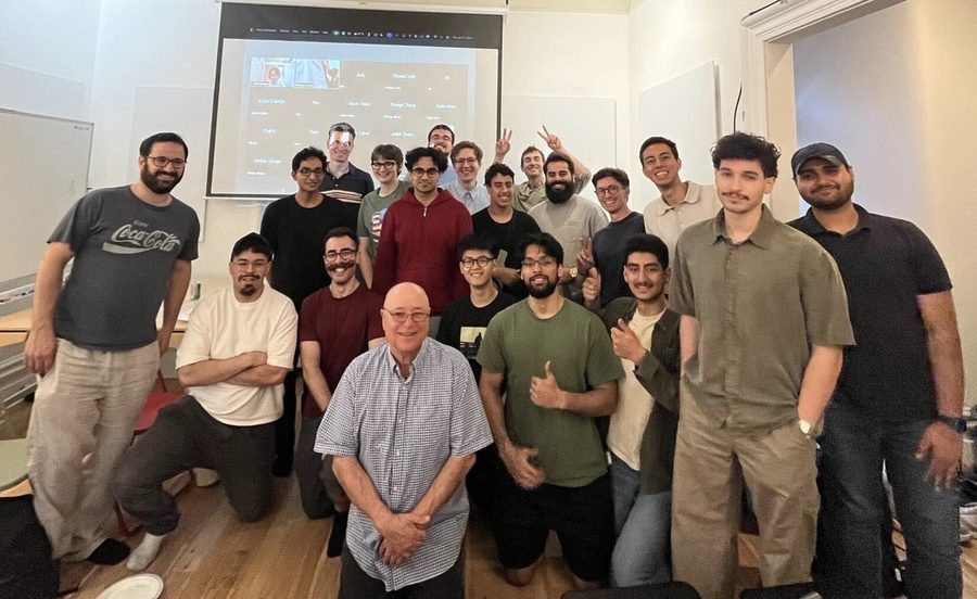 Des participants à un hackathon posant ensemble devant l’écran de projection