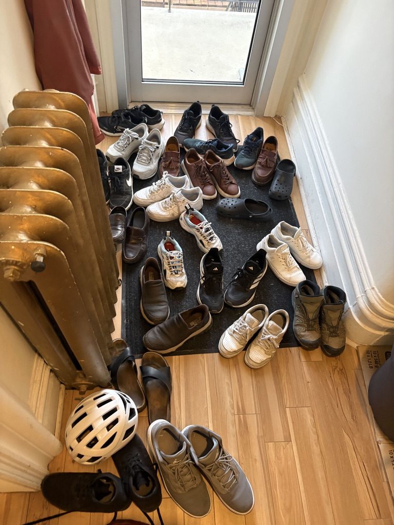Une pile de chaussures près du radiateur en fonte à l’entrée